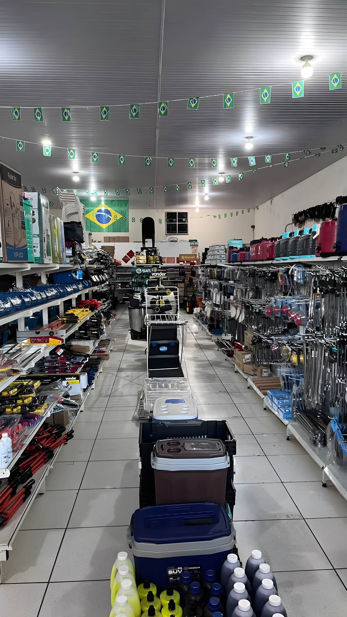 Corredor da loja com chaves, alicates, níveis e caixas térmicas nas prateleiras