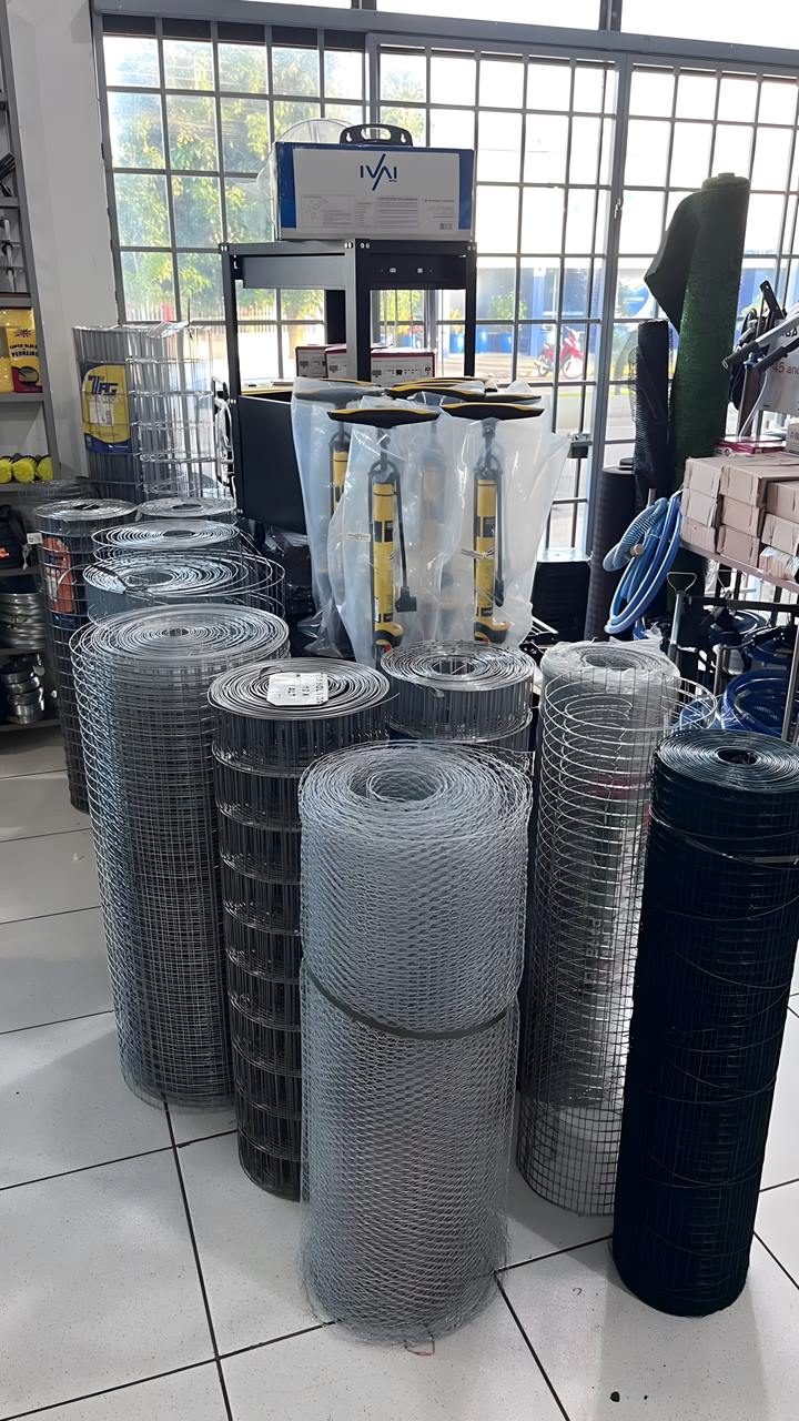 Rolos de tela soldada e tela de galinheiro em pé na frente da vitrine da loja